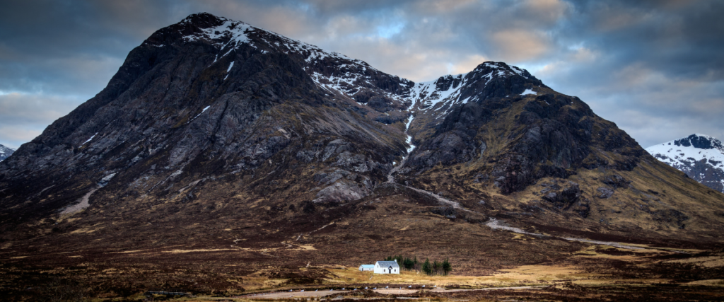 Photo of a small house in a remote mountain landscape in the Scottish highlands 